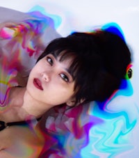 a woman laying in a bathtub with colorful liquids